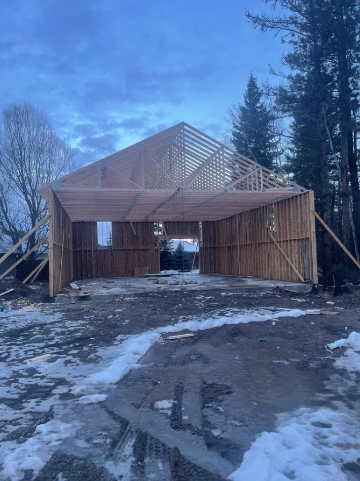 Timber-framed garage with trusses set at dusk in winter